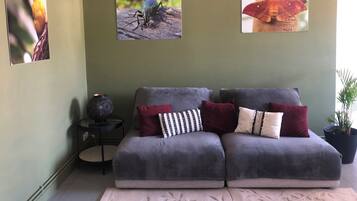 A living room with a grey sofa, a small side table, and a potted plant.