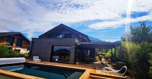 Uma casa moderna com piscina, deck de madeira e área de estar externa.