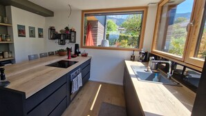 Una cocina moderna con una isla de madera, armarios negros y un ventanal que ofrece vistas al exterior.