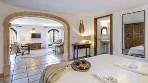 Une chambre d’hôtel comprenant un lit, un coin repas, une télévision, une salle de bain et un grand miroir.