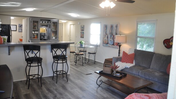 A compact living space with a kitchenette, a dining area, a sofa, and a ceiling fan.