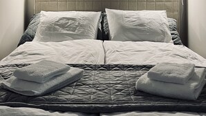 A neatly made bed with a quilted headboard, two bedside lamps, and a framed picture on the wall. - High-end, quiet, downtown home (Helsinki)