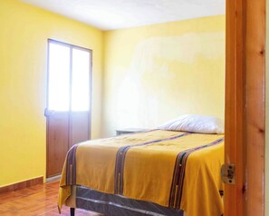 Une pièce avec un lit, une porte et une fenêtre.