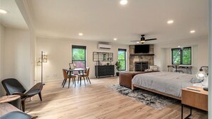 Une chambre spacieuse avec un grand lit, une cheminée, un coin repas avec des chaises et un téléviseur.