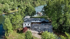 Une propriété située au bord du lac, avec une grande allée ouverte, un bâtiment blanc et une jetée qui s’avance dans l’eau.