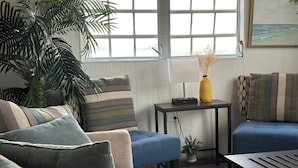 A living room with a sofa, a coffee table, a lamp, and a potted plant.