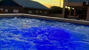 A swimming pool with a view of buildings and a sunset sky.