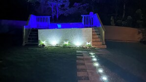 A small outdoor structure with a roof, steps leading up to it, and a pathway with lights.