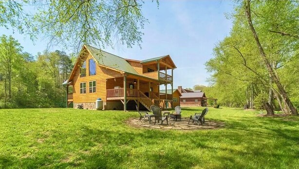 A wooden cabin with a porch and a fire pit area.