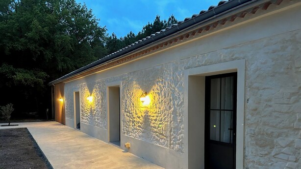 Een gebouw met een stenen gevel, meerdere deuren en buitenverlichting.