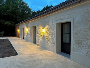 A building with a stone facade, multiple doors, and exterior lighting. - BERGERIE DE L OCEAN (Gaillan-en-Medoc)