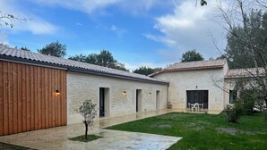 Een modern huis met een stenen gevel, een houten garagepoort en een klein terras met een tafel en stoelen.