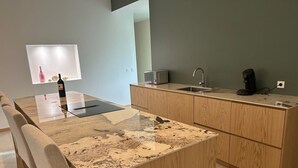 Een moderne keuken met een marmeren aanrecht, houten kastjes, een inbouwoven en een magnetron.