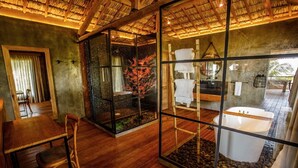 Un baño moderno con mampara de vidrio, una bañera y suelo de madera.