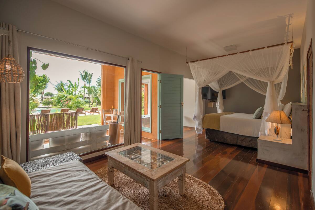 Un dormitorio con cama, una mesita de cristal, una mesita de noche y una cama con dosel.