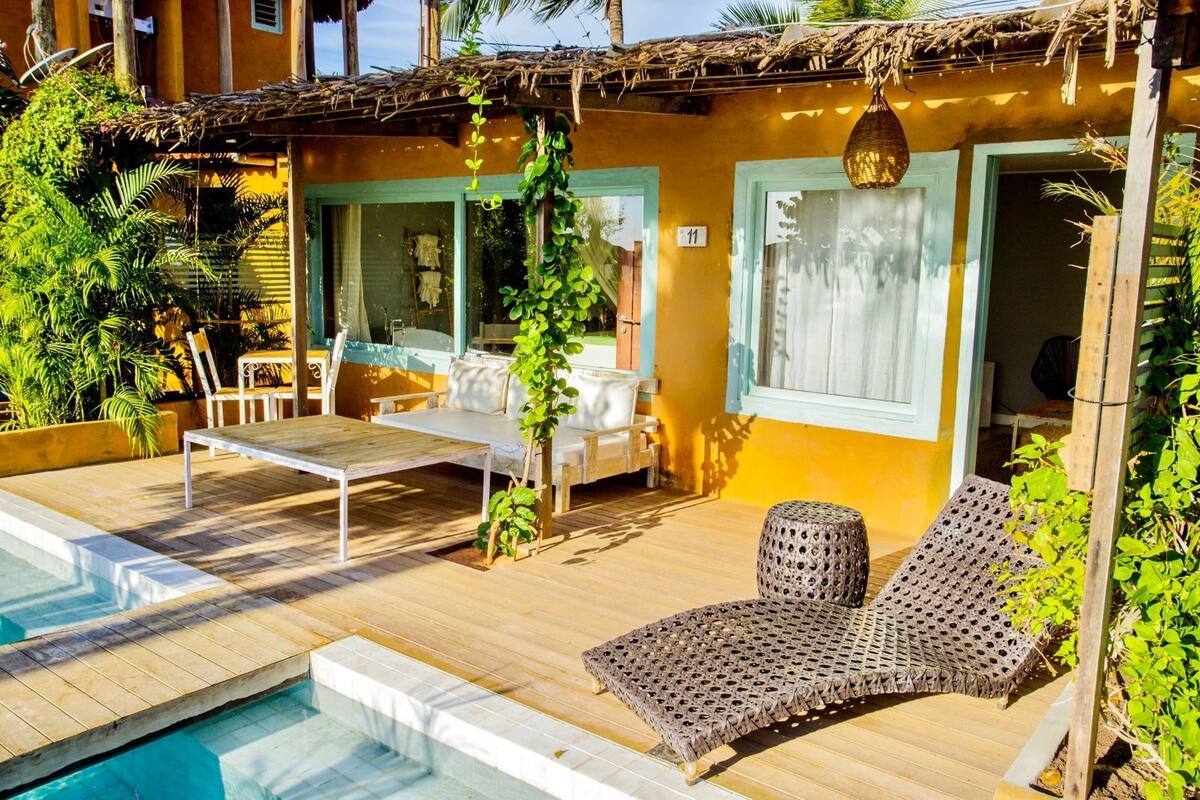 Zona de piscina con una silla de descanso, una mesa y una pequeña terraza.