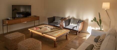 Una sala de estar moderna con un sofá, una mesa de centro y un televisor sobre un mueble de madera.