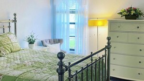 A bedroom with a bed, a dresser, a lamp, and a window with curtains. - Large 2 br n loft, 5 miles from downtown Naples 5th Avenue! On golf course (Naples)