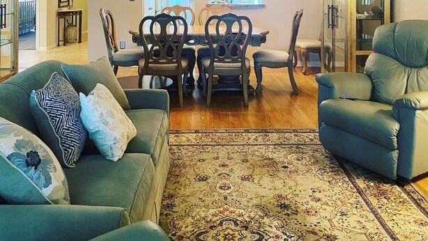A spacious living room with a high ceiling, a dining area with a wooden table and chairs, and a large window providing natural light. - Large 2 br n loft, 5 miles from downtown Naples 5th Avenue! On golf course (Naples)