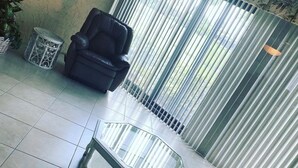 A living room with a black leather sofa, a glass-top coffee table, and a patterned sofa. - Large 2 br n loft, 5 miles from downtown Naples 5th Avenue! On golf course (Naples)