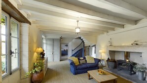 A spacious living room with a blue sofa, a wooden coffee table, and a fireplace. There is a staircase leading to another room. - VILLA CHEZ JENNY (Saint Privat en Périgord)