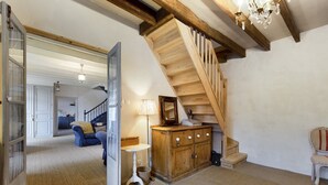 A spacious room with a wooden staircase, a small table, and a cabinet. - VILLA CHEZ JENNY (Saint Privat en Périgord)