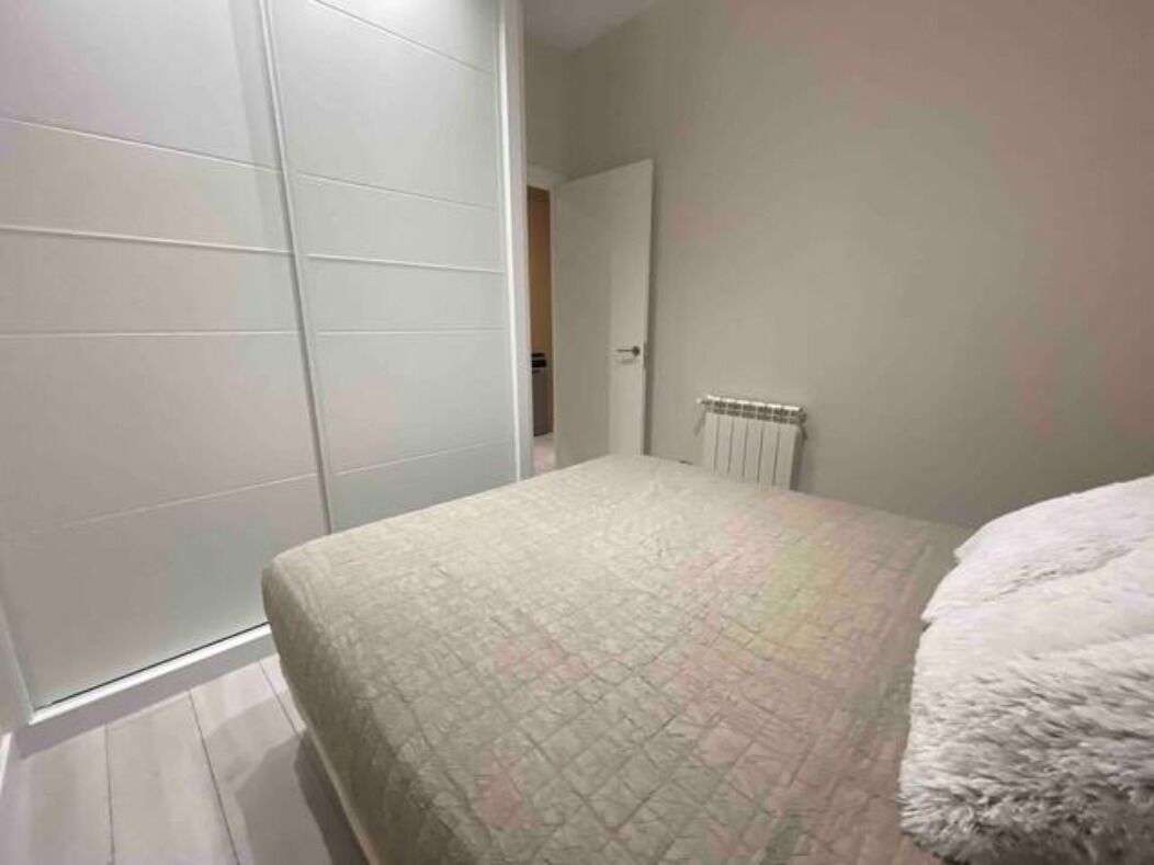 Un dormitorio con cama, un radiador y una puerta que da a otra habitación.