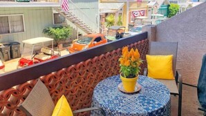 Un espace patio avec une table ronde, des coussins jaunes et une plante en pot.