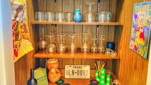 Une étagère avec différentes bouteilles, des verres et une plaque d’immatriculation du Texas.