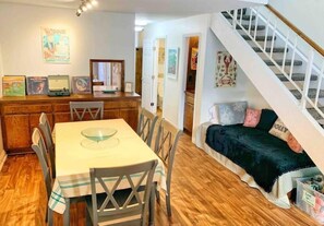 A dining area with a table and chairs, a wooden counter, and a staircase leading to another level.