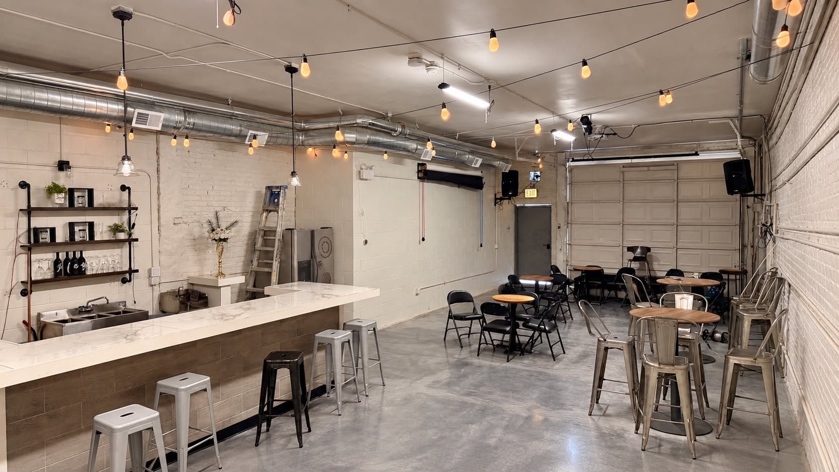 Un espace bar moderne doté d’un comptoir en marbre, de tabourets et de luminaires suspendus.