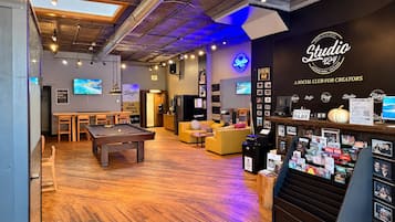 Un intérieur chaleureux avec une table de billard, des canapés et un panneau lumineux au néon indiquant « Studio 424 ».