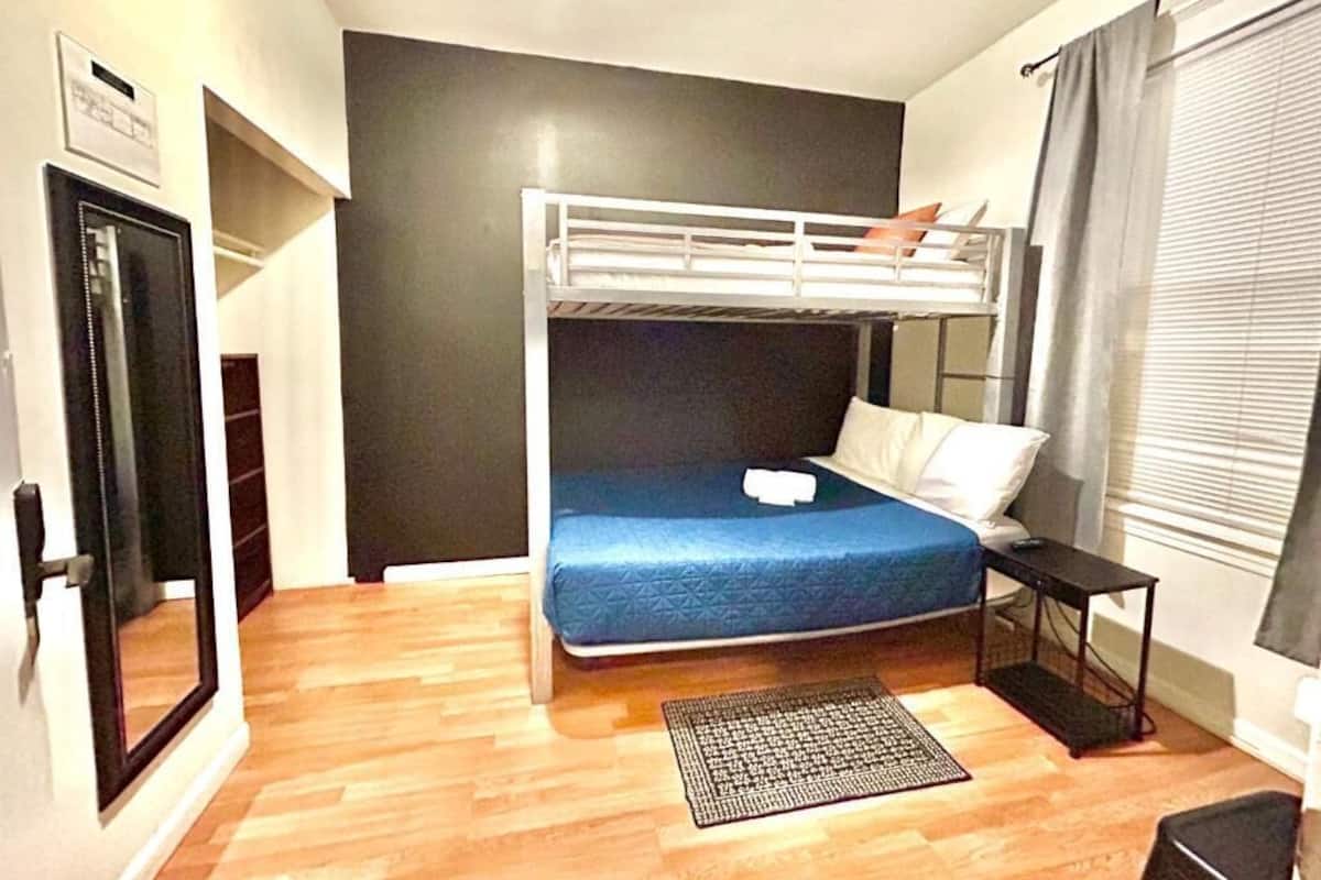Ein kleines Zimmer mit einer Etagenbett, einem kleinen Tisch, einem Teppich und einer Tür zu einem Balkon.