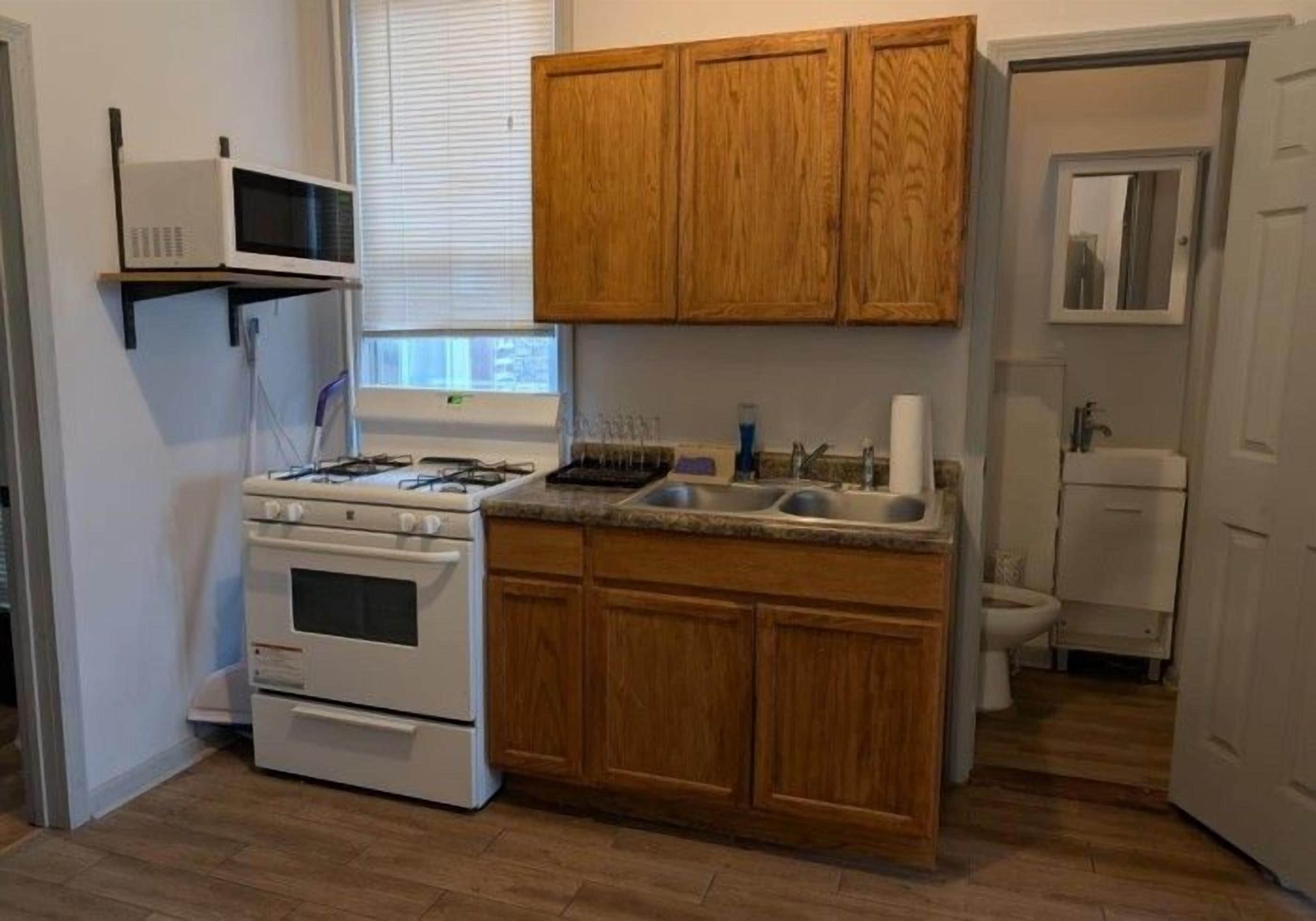 A compact kitchen with wooden cabinets, a built-in microwave, a stove, and a sink.