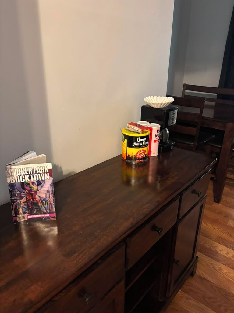 Une table en bois sur laquelle se trouvent un livre intitulé « Wicker Park Bucktown » et deux boîtes de café.