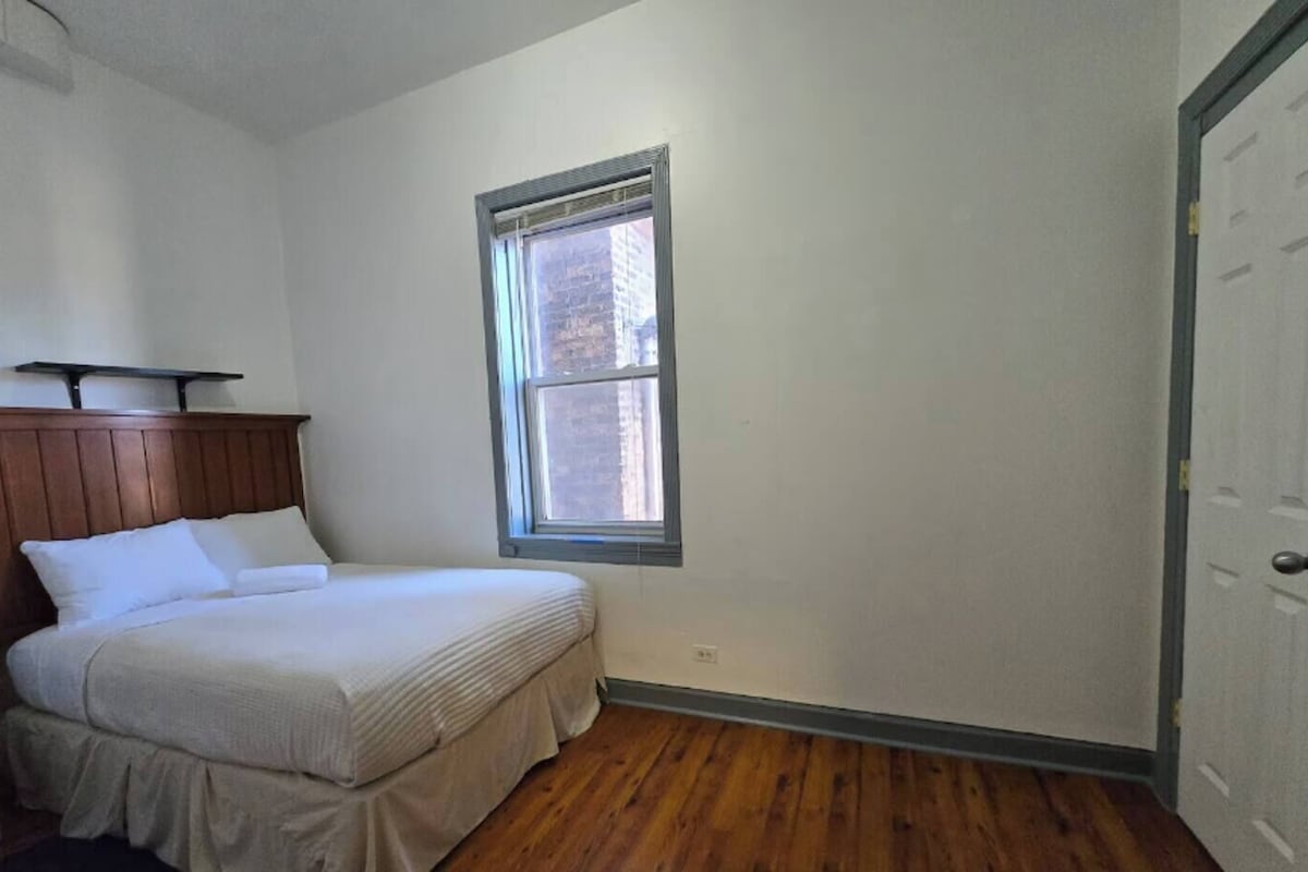A bedroom with a bed, a window, and a door.