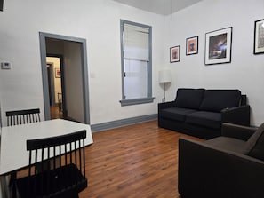 A living room with a dining table, two sofas, and a window with blinds. - STAY (Chicago)