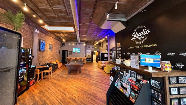 A modern lounge area with a pool table, seating, and a vending machine.