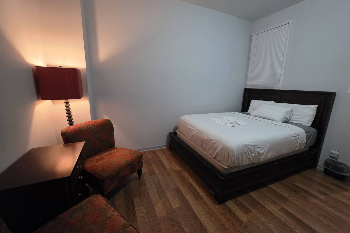 Ein Schlafzimmer mit Bett, Stuhl, Nachttisch und Lampe.