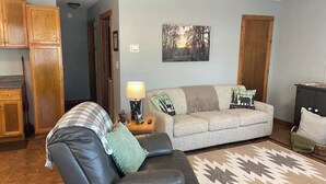 A living room with a sofa, a coffee table, a rug, and a painting on the wall. - A quiet retreat nestled right in the Hoosier National Forest. (Saint Croix)