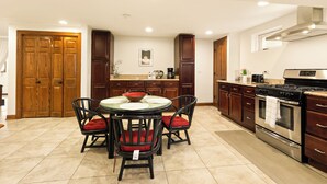 A kitchen with a round table, chairs, cabinets, a stove, and a coffee maker. - Luxury Suite in Glen Ellyn, IL USA (Glen Ellyn)