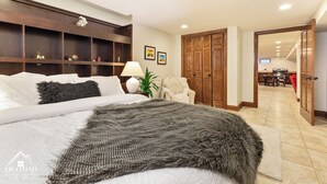 A bedroom with a large bed, a wooden headboard, a bedside table with a lamp, and a wall-mounted shelf. - Luxury Suite in Glen Ellyn, IL USA (Glen Ellyn)