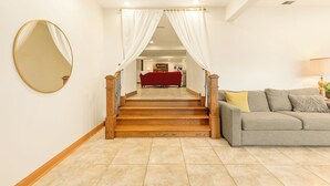A staircase with wooden steps and white curtains, leading to a red sofa and a grey couch in a well-lit room with tiled flooring. - Luxury Suite in Glen Ellyn, IL USA (Glen Ellyn)