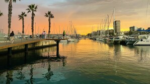 A marina with boats docked, palm trees, and a bridge. - San Francisco Home by Gloove (Alicante / Alacant)