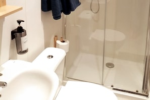 A modern bathroom with a glass shower enclosure, a white sink, and a toilet. - Casa Alba Mindelo (Vila do Conde)
