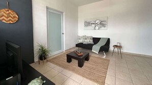 A modern living room with a sofa, coffee table, and a ceiling fan. - City Charm: Double BR San Juan Adventure, Sleeps 2 (San Juan)