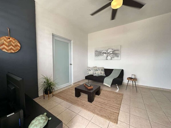 Un salon moderne avec un canapé, une table basse et un ventilateur de plafond.
