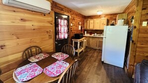 Ein Holzinnenraum mit einem für vier Personen gedeckten Esstisch, einem Kühlschrank und Holzschränken.