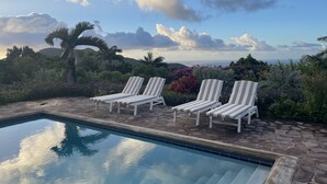 A pool area with lounge chairs and a view of the ocean. - Charming Nevis Cottage with pool and ocean view on grounds of Hermitage Inn (Gingerland)