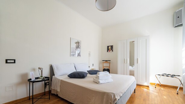 Un dormitorio con cama, mesita de noche y armario.